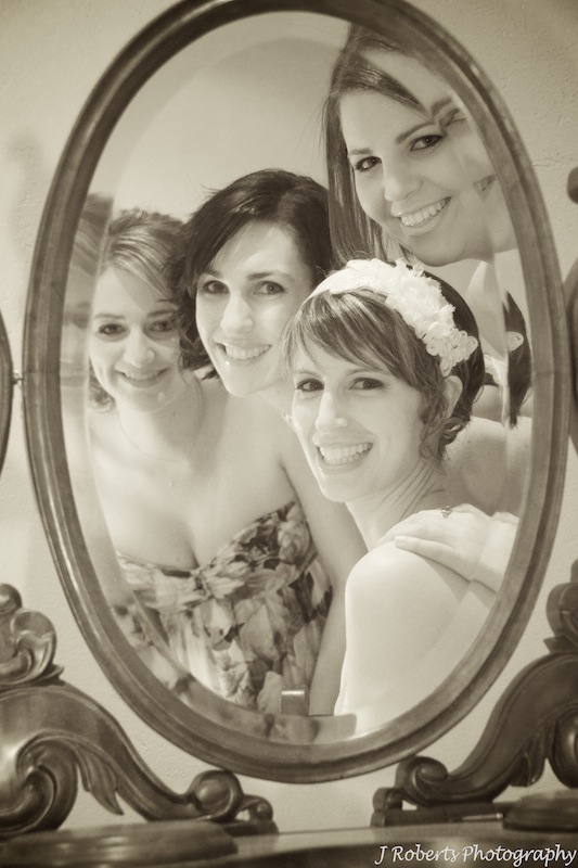 Bride and bridesmaids looking in mirror - wedding photography